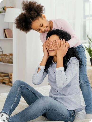 Criança cobre os olhos da mãe em um momento de brincadeira, representando afeto, confiança e vínculo familiar.