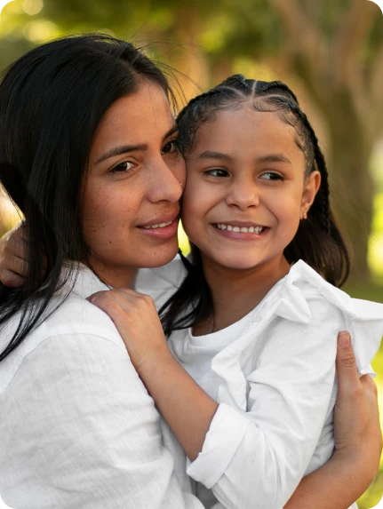 Mulher abraça carinhosamente sua filha sorridente, simbolizando proteção familiar e apoio jurídico no âmbito do Direito de Família.